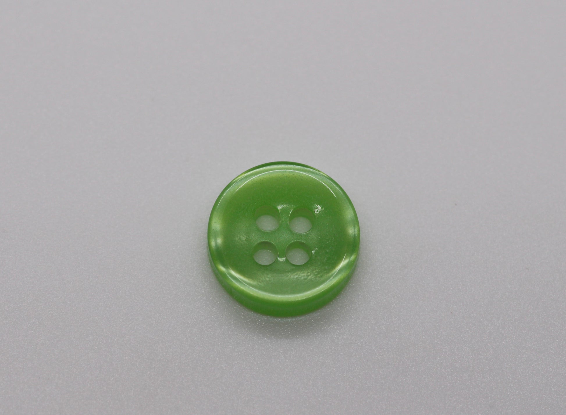 Close-up image of Green Iridescent 4-hole Button, a premium quality button.