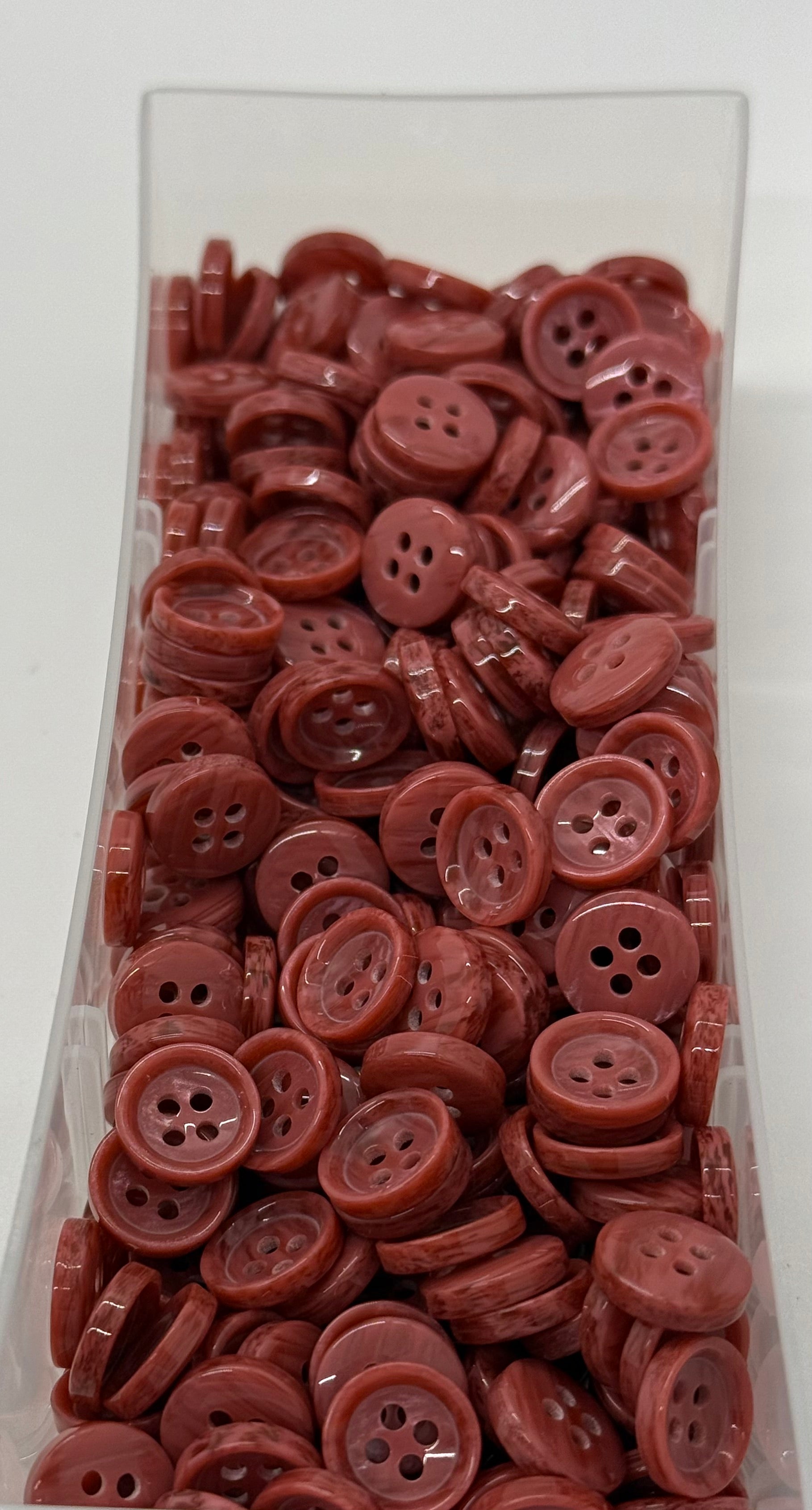 Close-up image of Terra Blush - Pale Red Dimble Button, a premium quality button.