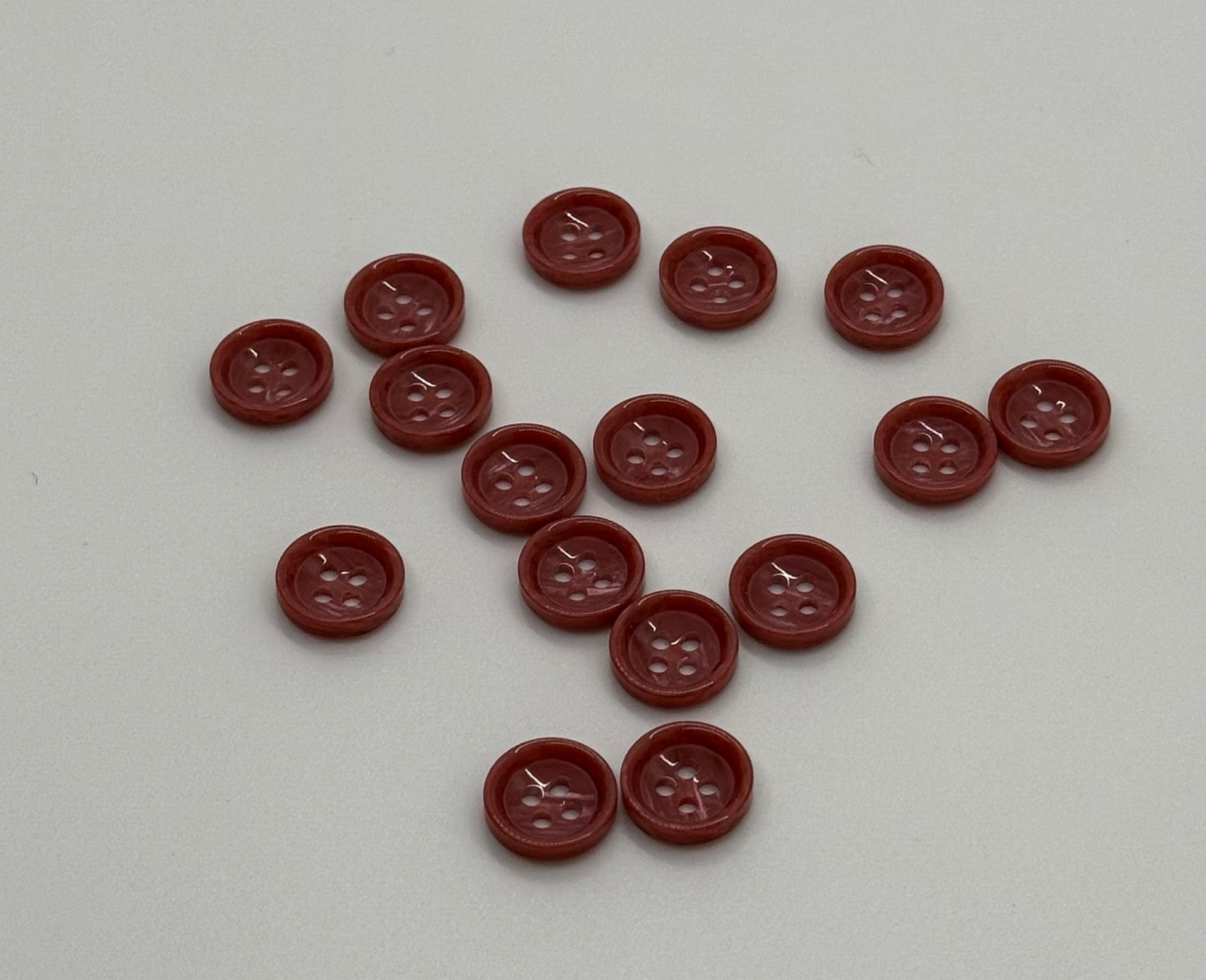 Close-up image of Terra Blush - Pale Red Dimble Button, a premium quality button.