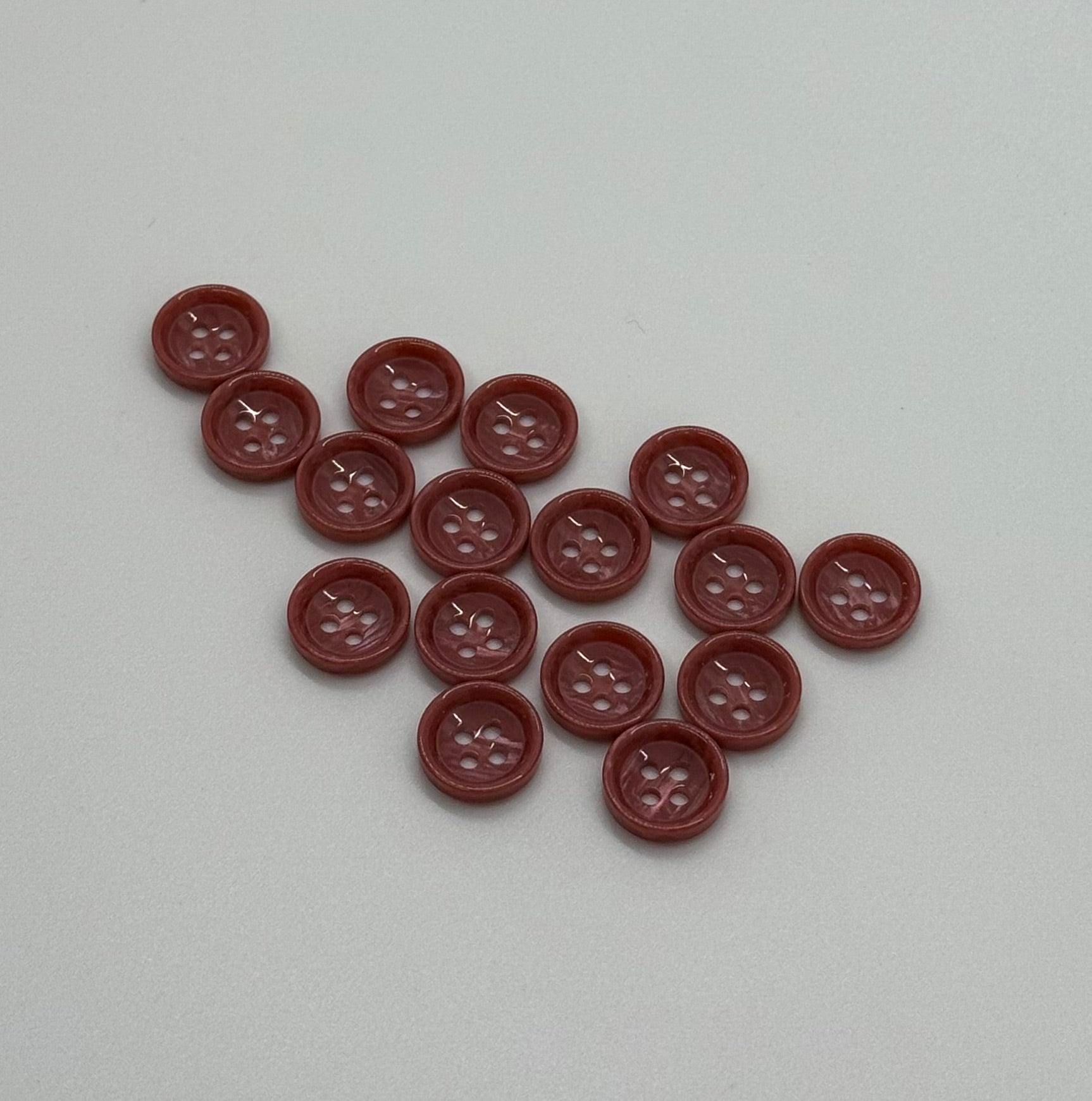 Close-up image of Terra Blush - Pale Red Dimble Button, a premium quality button.